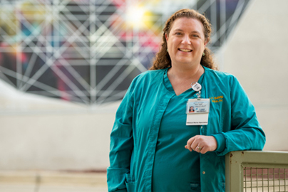 Anna Satake smiles in front of a mural
