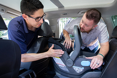 Two men installing a car seat.