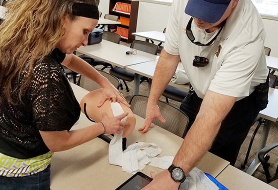 An instructor and student learning emergency techniques that stop bleeding. 