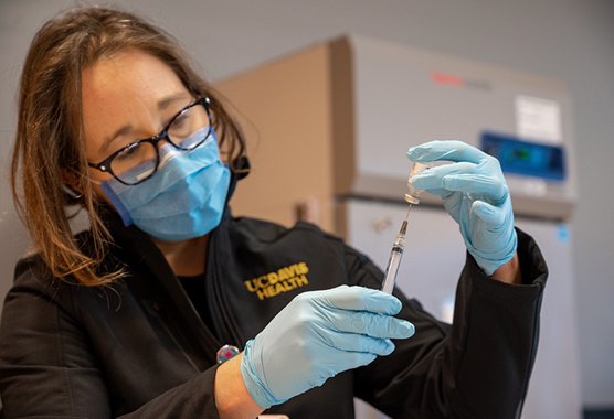 Woman filling a syringe from a medicine vial.