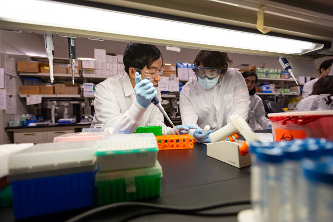 Lab worker moving a vile of blood.