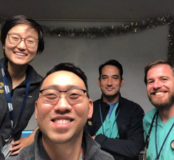 4 residents smiling in hospital with Christmas decorations behind