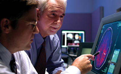 Researchers looking at an image of a brain scan on a screen.