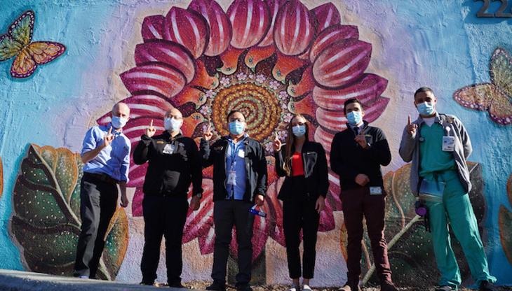 healthcare workers standing in front of a large mural