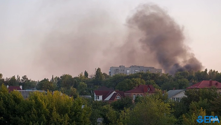 A wildfire burning close to homes with lots of smoke.