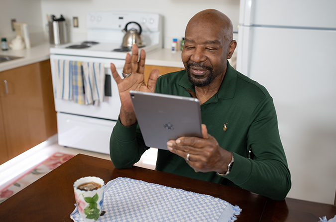 A man waving to his family member in the hospital, via an online app.