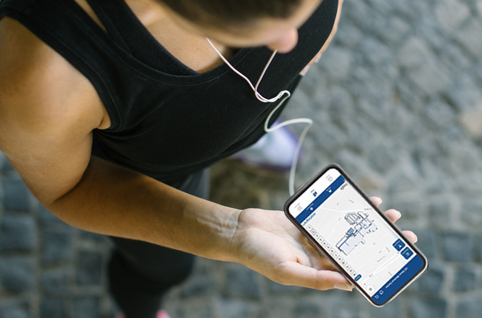 A woman holding a smart phone on displaying the find my way app.