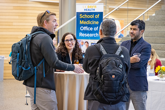 Medical colleagues standing around a small table having a casual conversation.