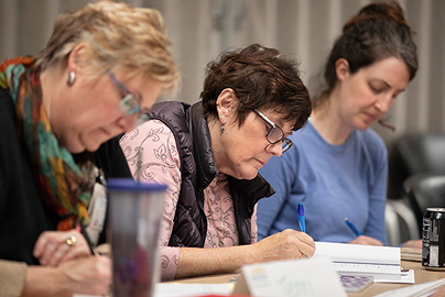 Three women sitting at a table writing.
