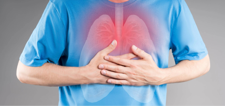 Person holds both hands over the center of the chest, with a semi-transparent overlay of the lungs highlighted in red as if inflamed or pained.