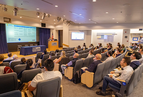 Annual cancer research symposium held in a small theater room.