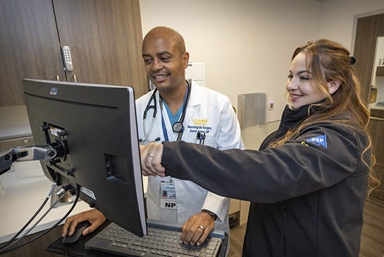 Two providers at computer screen for training program in health informatics