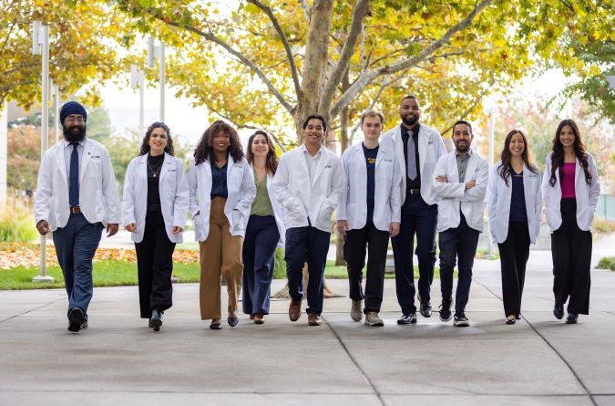 group of medical students in white jackets walking in a line towards the camera