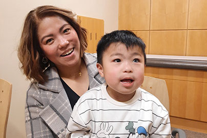 Mother and genomic child patient sits on mom's lap.