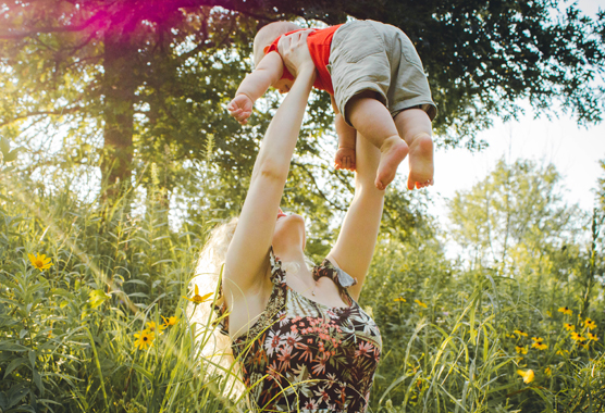 woman holding up child in a field