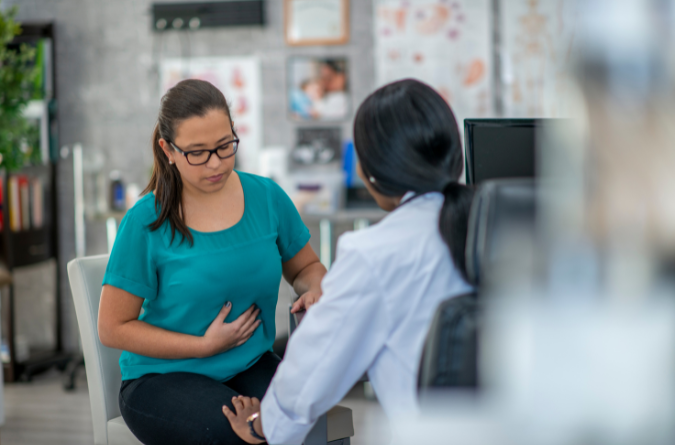 A woman speaks with her doctor in a bright room. 
