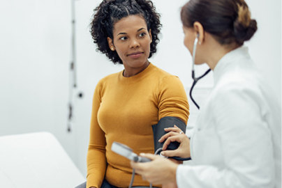 A female patient has her blood pressure checked by a female doctor.