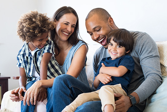 Happy parents holding two boys on couch 