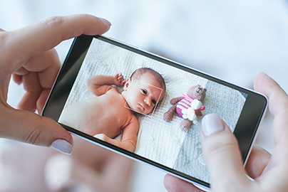 Mom holding phone showing baby in NICU bed