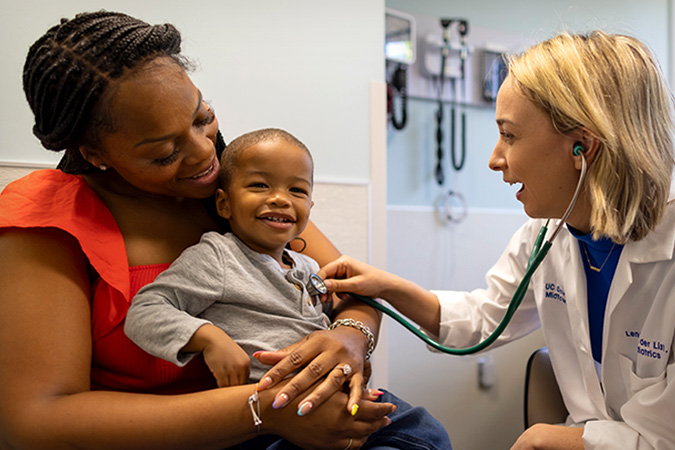 UC Davis pediatrician with young todler and mom in clinic office.