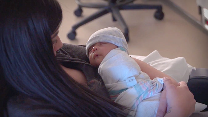 Mother holding infant in NICU