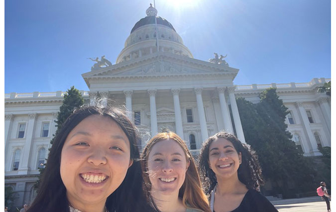 Three residents pose in front of California Capitol Building.