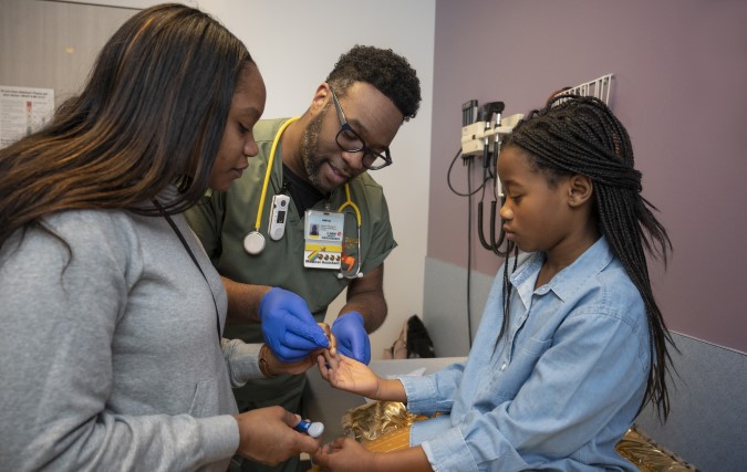 Doctor and female pediatric patient with parent, test blood from finger.