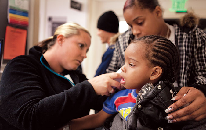 Female nurse checks small boy patient's ear with mom close by