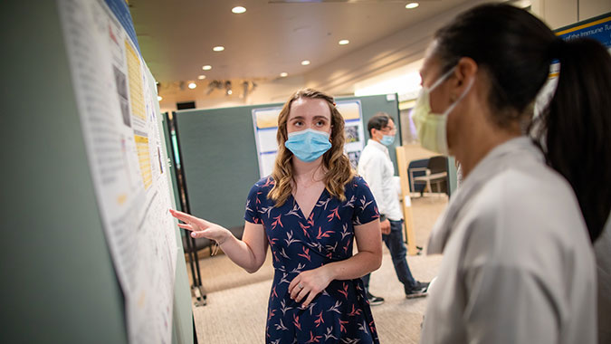 Female fellow displays scholarly project posters to audience