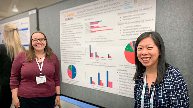 Two female residents display their scholarly project on on a brown white board.
