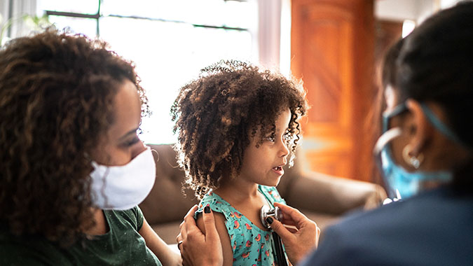 Mother with child visits doctor in hospital room.