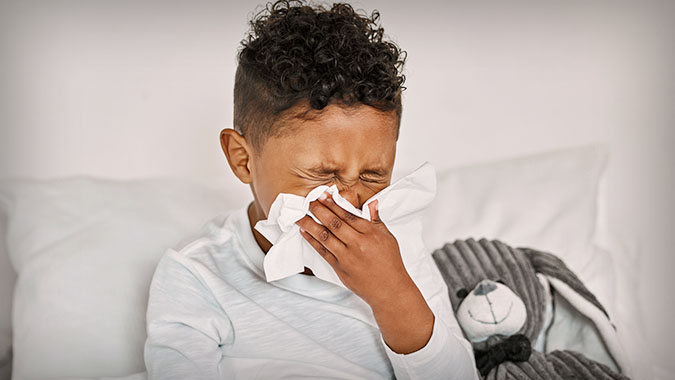 Child sneezing, in bed