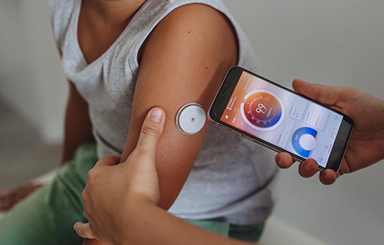 Pediatric child with insulin port being read with cell phone.