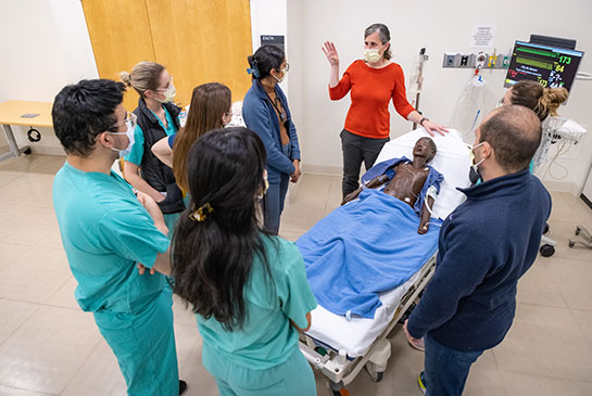 Six Pediatric Hospital Medicine team members learn from female professor using patient dummy