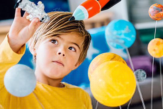 Young child playing with astronaut, spaceship and planets