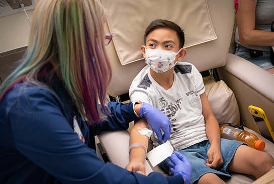 UC Davis oncologist drawing blood from pediatric patient.