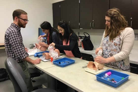 Faculty teaches while residents practice on simulation equipment.