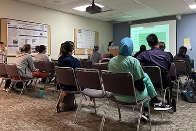 Residents sit in conference room watching presenter and projected presentation.