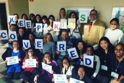 Residents and patients hold up signs that reads, Keep Kids Covered.