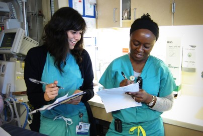 Two NICU residents fill out charts in hospital hallway.