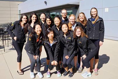 Thirteen residents pose outside of hospital in black UCDH jackets.