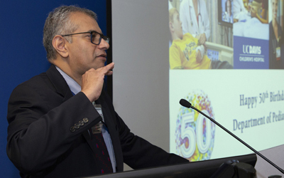 Grand Rounds conference doctor presents at podium with projection screen behind displays research.