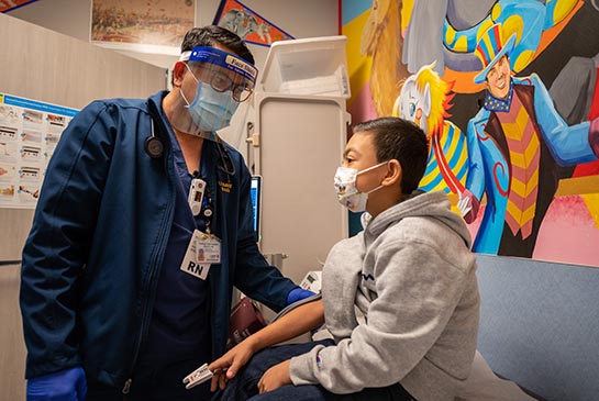 Perinatal dialysis nurse with pediatric patient in hospital room.