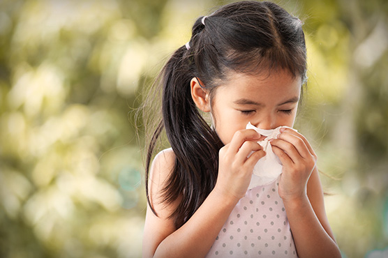 Young girl sneezing outdoors