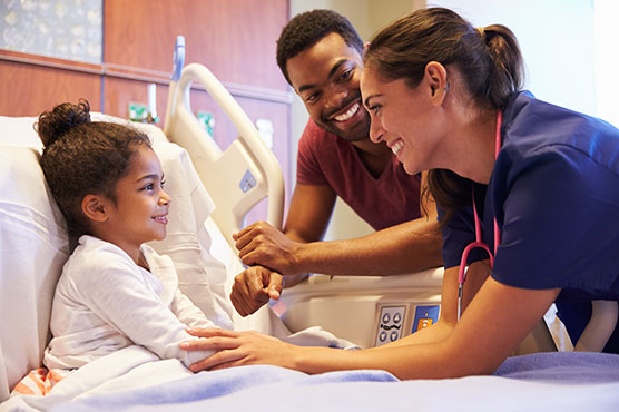 Young girl patient in hospital bed with nurse and doctor smiling