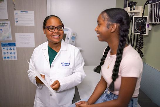 Adolescent female in clinic speaking with physician.