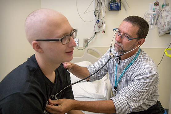 Dr. Marcio Malogolowkin examines patient in hospital room.