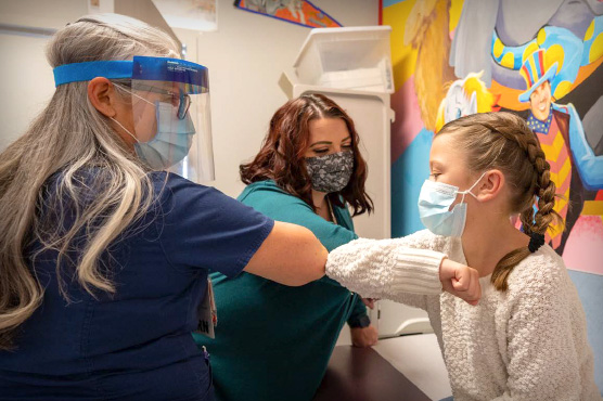 Two nephrology team members with young kidney patient in medical room.