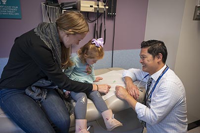 Doctor examines baby while mother holds baby in her arms.