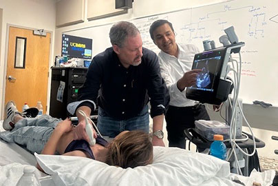 Ultrasound demonstration with nurse, doctor, and patient in hospital bed next to monitor